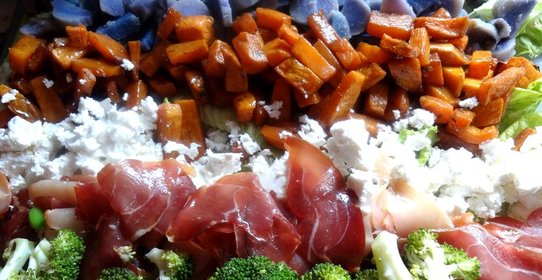 Слоеный овощной салат с прошутто и фетой на доске