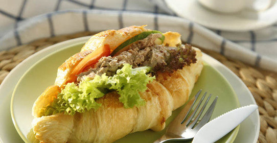 Круассан с тунцом, листьями салата и помидором