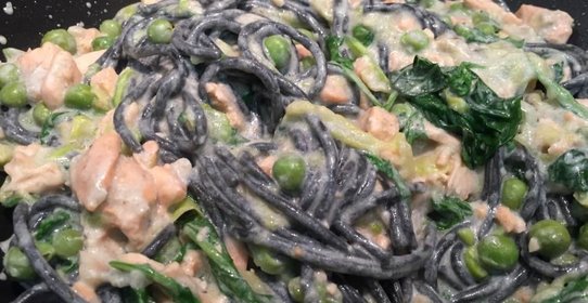 Черные спагетти с красной рыбой, зелёным горошком и голубым сыром