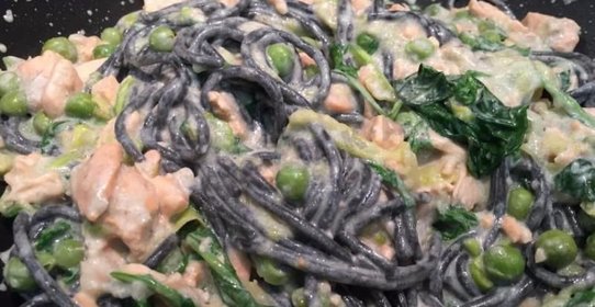 Черные спагетти с красной рыбой зелёным горошком и голубым сыром